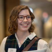An alum smiles during a conversation while holding her program